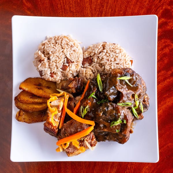 Flavas Jamaican Grill's oxtail stew with rice and peas, fried plantains, and garnished with peppers.